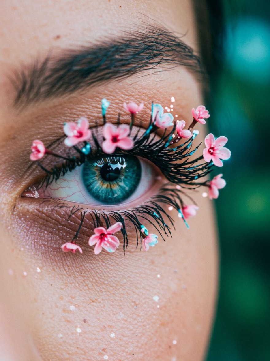 Русский промпт: A close-up of a woman's eye with a beautiful blue iris, adorned with pink and blue floral embellishments. Her eyelashes are long and full, and she has a subtle, glittery effect on her eyelid. The background is blurred, with a soft, green hue. The lighting is soft and natural, highlighting her delicate features. The overall aesthetic is dreamy and ethereal. | Original prompt: A close-up of a woman's eye with a beautiful blue iris, adorned with pink and blue floral embellishments. Her eyelashes are long and full, and she has a subtle, glittery effect on her eyelid. The background is blurred, with a soft, green hue. The lighting is soft and natural, highlighting her delicate features. The overall aesthetic is dreamy and ethereal.