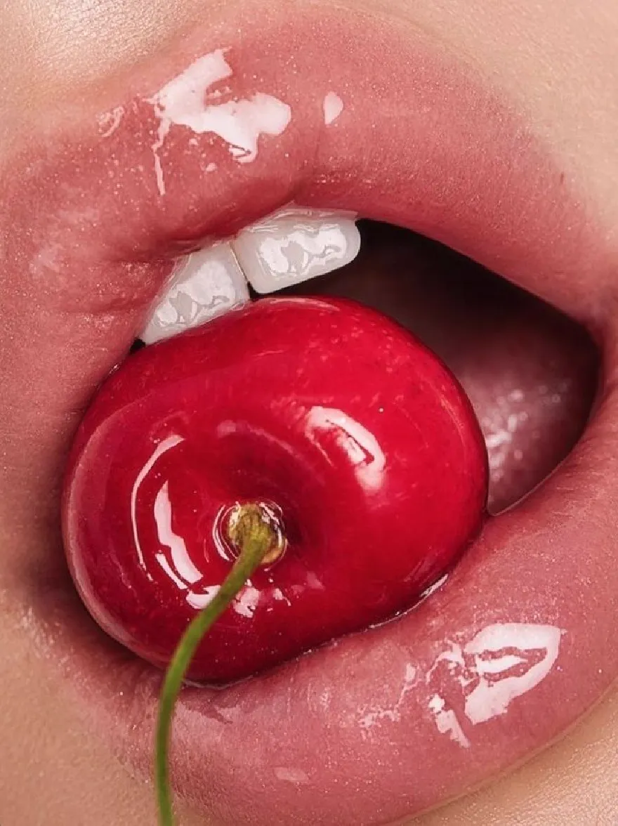 Русский промпт: A close-up photograph of a woman's mouth with a bright red cherry in her mouth. The cherry is placed in the center of her mouth, with its stem still attached. The lips are full and glossy, with a light pink hue. The background is blurred, allowing the focus to remain on the cherry and the woman's lips. The lighting is soft and natural, highlighting the texture of the cherry's skin. The overall mood is sensual and playful. | Original prompt: A close-up photograph of a woman's mouth with a bright red cherry in her mouth. The cherry is placed in the center of her mouth, with its stem still attached. The lips are full and glossy, with a light pink hue. The background is blurred, allowing the focus to remain on the cherry and the woman's lips. The lighting is soft and natural, highlighting the texture of the cherry's skin. The overall mood is sensual and playful.