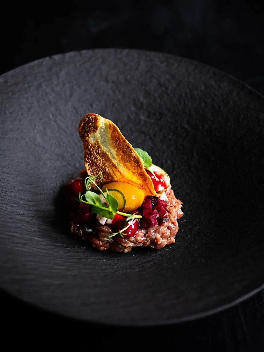 Русский промпт: Фотография тарелки с едой на темной черной тарелке, установленной на темном фоне. Пластина имеет прямоугольную форму и имеет темную текстурированную поверхность. На вершине тарелки наверху есть кусок жареного яйца, окруженное кроватью ризотто с пюре из свеклы и дождь томатного соуса. Ризотто украшено брызгом из листьев мяты. Яйцо приготовлено до совершенства, с золотисто-коричневой корочкой и сочным, жидким желтком. Блюдо выглядит аппетитным и визуально привлекательным. Освещение мягкое и естественное, подчеркивая текстуру ризотто и яркие цвета ингредиентов. | Original prompt: A photograph of a plate of food on a dark black plate, set against a dark background. The plate is rectangular in shape and has a dark, textured surface. On top of the plate, there is a piece of fried egg on top, surrounded by a bed of risotto with beetroot puree and a drizzle of tomato sauce. The risotto is garnished with a sprinkle of mint leaves. The egg is cooked to perfection, with a golden-brown crust and a juicy, runny yolk. The dish looks appetizing and visually appealing. The lighting is soft and natural, highlighting the texture of the risotto and the vibrant colors of the ingredients.