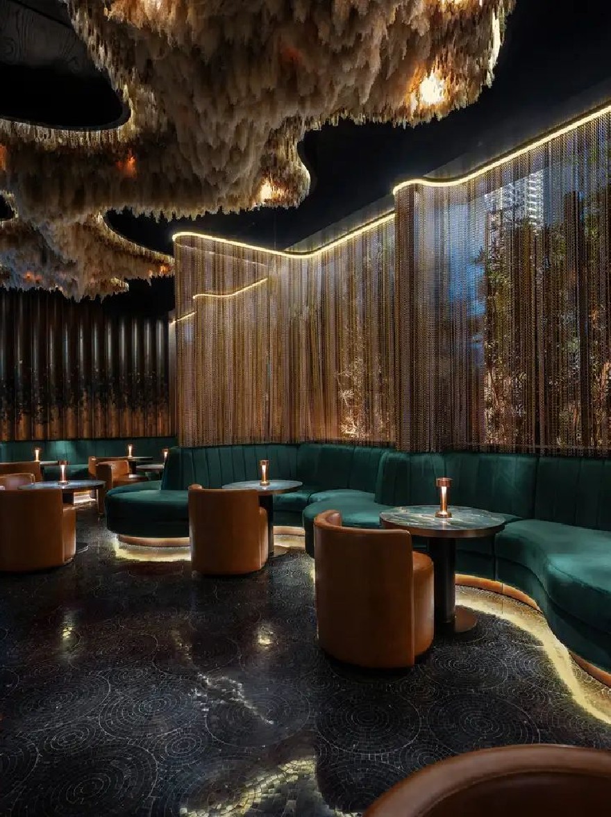 Русский промпт: На изображении показан роскошный, слабо освещенный ресторан с темным мраморным полом, зелеными бархатными стендами и коричневыми кожаными стульями, расположенными вокруг круглых столов. Стены украшены золотыми блестками, которые создают мерцающий эффект, а потолок украшен большой пернатой люстра. Атмосфера утончена и привлекательна, идеально подходит для ночи. Освещение мягкое и теплое, создавая уютную атмосферу. Общий дизайн современный и сложный. | Original prompt: The image shows a luxurious, dimly lit restaurant with a dark, marble floor, green velvet booths, and brown leather chairs arranged around round tables. The walls are adorned with gold sequins that create a shimmering effect, and the ceiling is decorated with a large, feathered chandelier. The atmosphere is sophisticated and inviting, perfect for a night out. The lighting is soft and warm, creating a cozy ambiance. The overall design is modern and sophisticated.