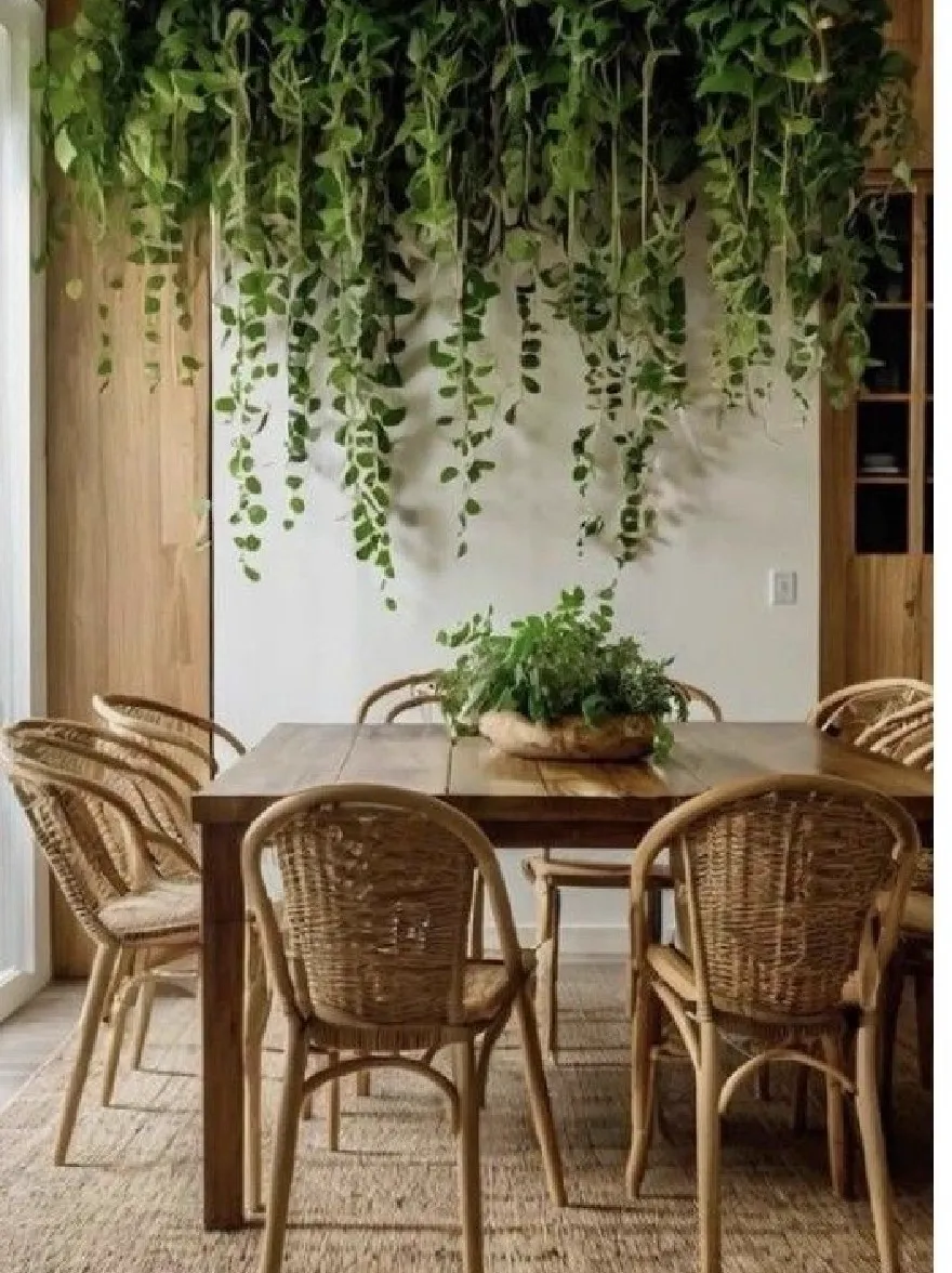Русский промпт: Деревенская столовая с деревянным столом и шестью плетеными стульями, тканым ковром и горшечным растением на столе. На потолке висят пышные зеленые растения, добавляя в комнату прикосновение природы. Стены изготовлены из светлого дерева, а на левой стороне комнаты есть раздвижная стеклянная дверь, что позволяет войти естественным светом. Общая эстетика уютная и привлекательная, идеально подходит для расслабляющих и развлекательных гостей. | Original prompt: A rustic dining room with a wooden table and six wicker chairs, a woven rug, and a potted plant on the table. Hanging from the ceiling are lush green plants, adding a touch of nature to the room. The walls are made of light-colored wood, and there is a sliding glass door on the left side of the room, allowing natural light to enter. The overall aesthetic is cozy and inviting, perfect for relaxing and entertaining guests.