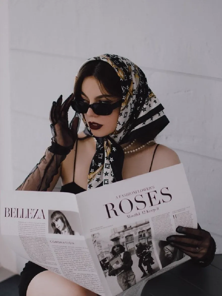 Русский промпт: Photo of a woman sitting on a chair, reading a newspaper, wearing a black dress, black gloves, and a scarf with a yellow and white pattern. She has dark hair styled in a bob cut, and is wearing black sunglasses. The background is a plain white wall. The woman is holding the newspaper in front of her face, with the headline "Belleza" and "Roses" visible. The lighting is soft and natural, highlighting her features. The image has a minimalist aesthetic, with a focus on the woman's face and the newspaper. | Original prompt: Photo of a woman sitting on a chair, reading a newspaper, wearing a black dress, black gloves, and a scarf with a yellow and white pattern. She has dark hair styled in a bob cut, and is wearing black sunglasses. The background is a plain white wall. The woman is holding the newspaper in front of her face, with the headline "Belleza" and "Roses" visible. The lighting is soft and natural, highlighting her features. The image has a minimalist aesthetic, with a focus on the woman's face and the newspaper.