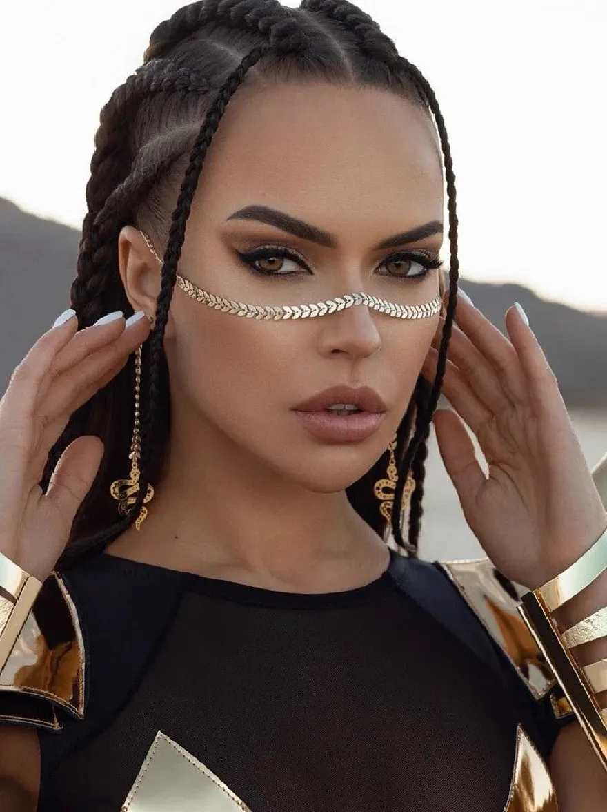 Русский промпт: Фотография красивой афро-американской женщины с длинными плетеными волосами, одетая в черный и золотой наряд с геометрическим дизайном. У нее серьезное выражение, и она держит волосы обеими руками. Фон размыт, но, похоже, это наружная обстановка с горами на расстоянии. Освещение мягкое и естественное, подчеркивая ее черты. Изображение высокое качество и имеет профессиональное чувство. | Original prompt: Photo of a beautiful African-American woman with long braided hair, wearing a black and gold outfit with a geometric design. She has a serious expression and is holding her hair with both hands. The background is blurred, but it appears to be an outdoor setting with mountains in the distance. The lighting is soft and natural, highlighting her features. The image is high quality and has a professional feel.