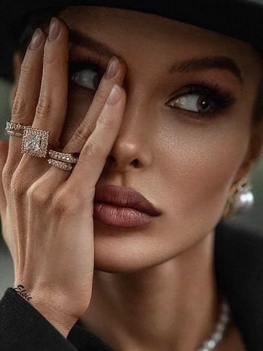 Русский промпт: Фото женщины с темной кожей, в черной шляпе, черном топе и жемчужного ожерелья. У нее серьезное выражение, когда ее глаза смотрят прямо на камеру. Ее руки сложены вместе перед ее лицом, и у нее на левой руке кольцо. Фон размыт, но он, кажется, находится в помещении. Освещение мягкое и естественное, подчеркивая ее черты. Изображение имеет минималистскую эстетику, с акцентом на лицо женщины и украшения. | Original prompt: Photo of a woman with dark skin, wearing a black hat, a black top, and a pearl necklace. She has a serious expression, with her eyes looking directly at the camera. Her hands are clasped together in front of her face, and she has a ring on her left hand. The background is blurred, but it appears to be an indoor setting. The lighting is soft and natural, highlighting her features. The image has a minimalist aesthetic, with a focus on the woman's face and jewelry.