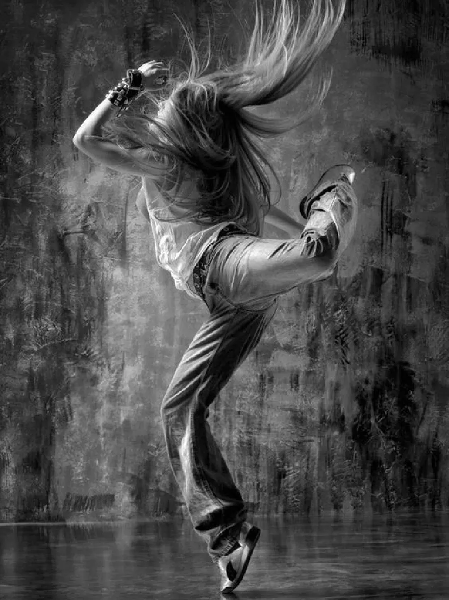 Русский промпт: Черно -белая фотография молодой женщины, прорывающейся в динамичной позе, с ее длинными, простыми волосами, дующих на ветру. На ней белая майка без рукавов и джинсы с жаркими джинсами в паре с черными туфлями. Фон представляет собой текстурированную бешеную бетонную стену с отражающей поверхностью, создавая драматический эффект освещения. Женщина находится в центре рамы, лицом от камеры, а ее руки растянуты до бок. Освещение драматичное, подчеркивая ее движения и создавая чувство движения и энергии. Общее настроение - это энергия и волнение. | Original prompt: A black and white photograph of a young woman breakdancing in a dynamic pose, with her long, flowing hair blowing in the wind. She is wearing a sleeveless white tank top and loose-fitting jeans, paired with black shoes. The background is a textured, grungy concrete wall with a reflective surface, creating a dramatic lighting effect. The woman is in the center of the frame, facing away from the camera, and her arms are stretched out to the sides. The lighting is dramatic, highlighting her movements and creating a sense of movement and energy. The overall mood is one of energy and excitement.