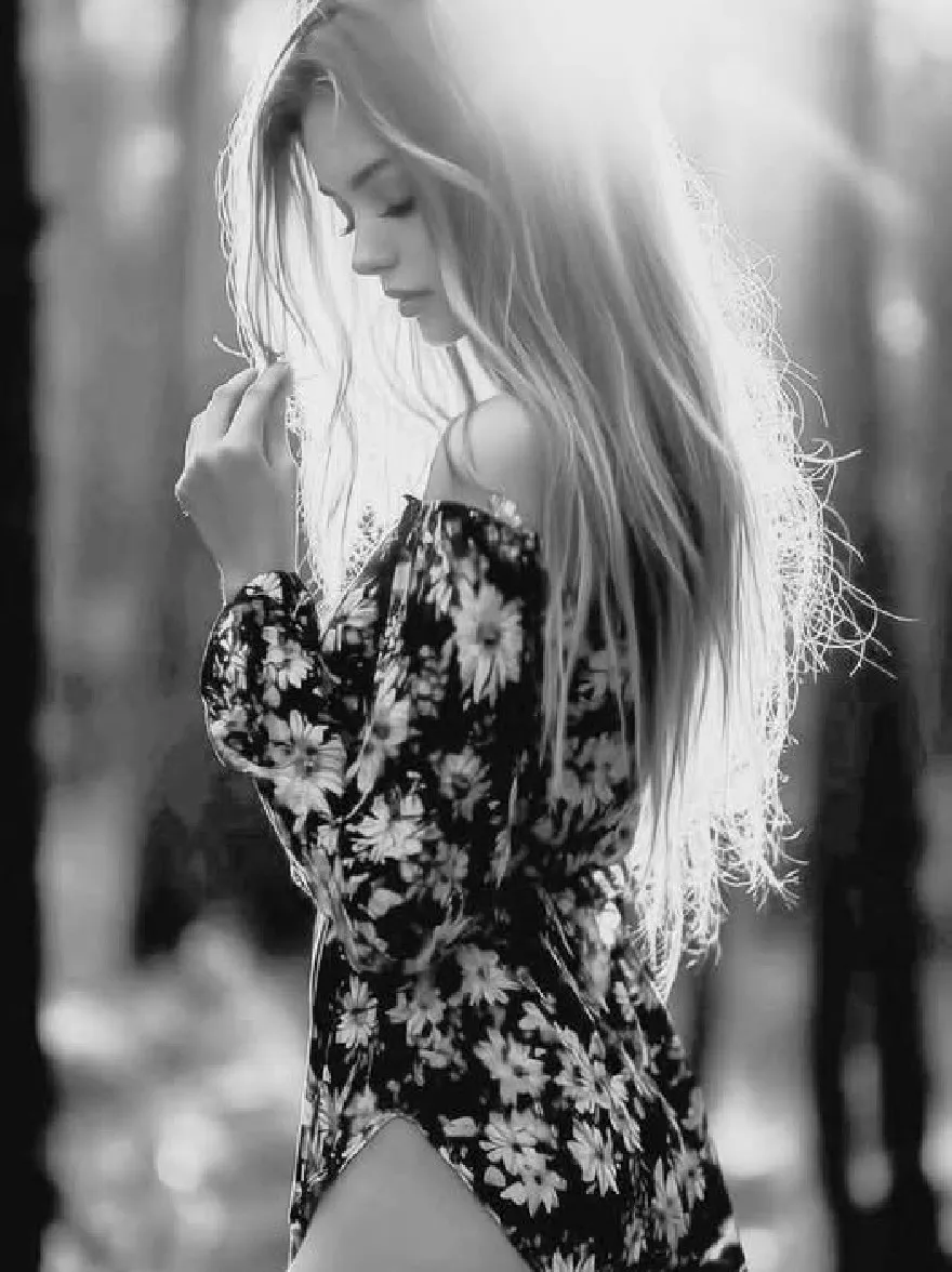 Русский промпт: Черно-белая фотография молодой женщины с длинными волнистыми светлыми волосами с цветочным платье с открытыми плечами. Она стоит в лесистой местности, глядя вниз с созерцательным выражением. Фон размыт, с солнечным светом профильтровывает по деревьям, создавая мягкое, эфирное сияние. У женщины есть честная кожа и стройное телосложение. Общее настроение мирное и безмятежное. | Original prompt: A black and white photograph of a young woman with long, wavy blonde hair, wearing a floral off-the-shoulder dress. She is standing in a wooded area, looking down with a contemplative expression. The background is blurred, with sunlight filtering through the trees, creating a soft, ethereal glow. The woman has fair skin and a slender physique. The overall mood is peaceful and serene.