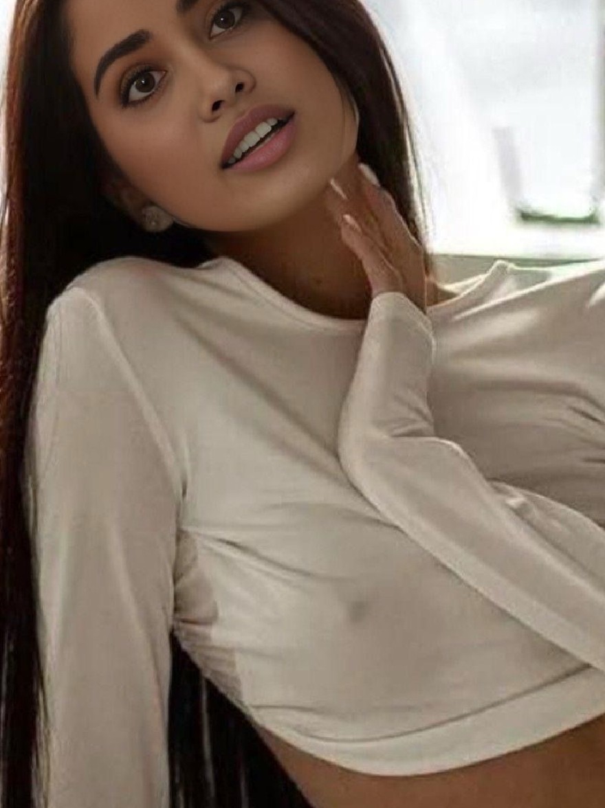 Русский промпт: Фотография молодой женщины с длинными, темно-коричневыми волосами и честной кожей, в белом, с длинным рукавым топом, который слегка наклонен в сторону, показывая ее руку, осторожно касающуюся ее подбородка. Она имеет нейтральное выражение и смотрит прямо на камеру. Фон размыт, но, кажется, это крытая обстановка с естественным светом, исходящим из окна. Освещение мягкое и естественное, создавая теплую и привлекательную атмосферу. Женщина имеет стройное телосложение и носит минимальный макияж. Изображение высокое качество и имеет профессиональный, отточенный вид. | Original prompt: Photo of a young woman with long, straight, dark brown hair and fair skin, wearing a white, long-sleeved crop top that is slightly tilted to the side, showing her hand gently touching her chin. She has a neutral expression and is looking directly at the camera. The background is blurred, but it appears to be an indoor setting with natural light coming from a window. The lighting is soft and natural, creating a warm and inviting atmosphere. The woman has a slender physique and is wearing minimal makeup. The image is high quality and has a professional, polished look.