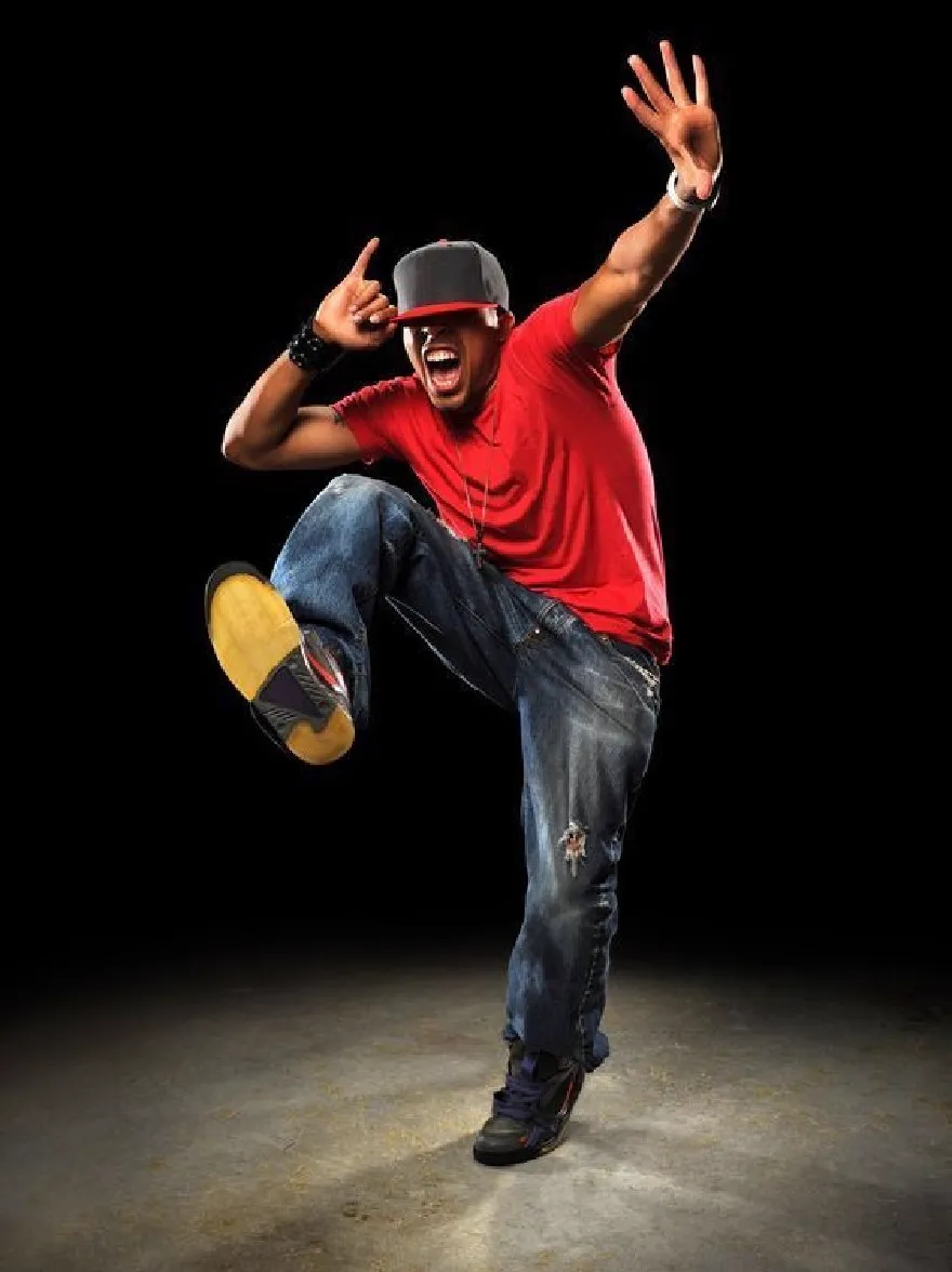 Русский промпт: Человек в динамичной позе, прыгающий в воздухе, а руки растянулись вверх. Он носит красную футболку, синие джинсы и черную бейсболку. Фон - твердый черный, а освещение драматично, отбрасывая тени на пол. У этого человека есть уверенное и энергичное выражение, с его ртом, открытым в реве. Изображение имеет высококачественный, профессиональный вид. | Original prompt: A man in a dynamic pose, jumping in the air with his arms stretched upwards. He is wearing a red t-shirt, blue jeans, and a black baseball cap. The background is a solid black, and the lighting is dramatic, casting shadows on the floor. The man has a confident and energetic expression, with his mouth open in a roar. The image has a high-quality, professional look.