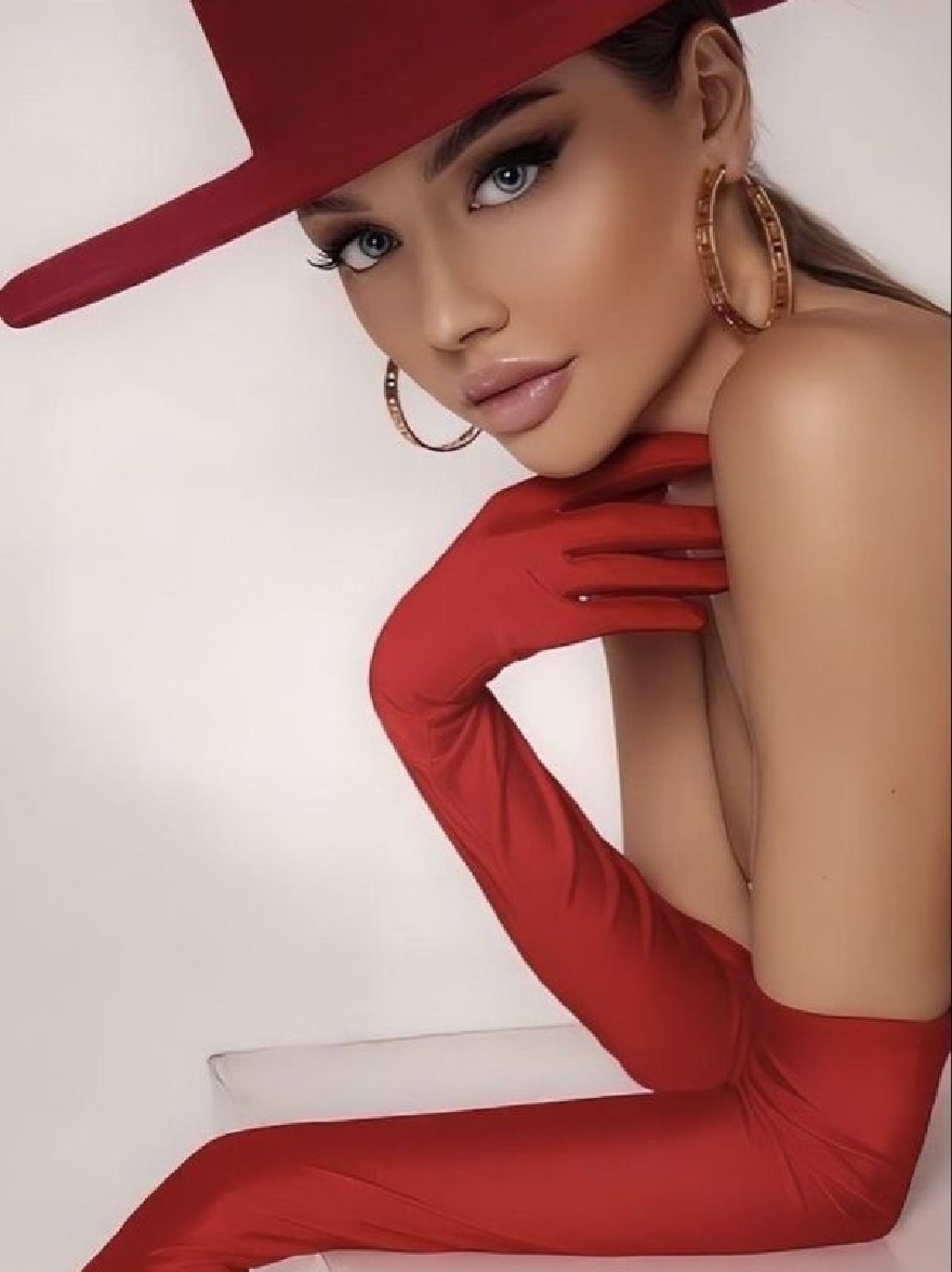 Русский промпт: Photo of a beautiful African-American woman with fair skin and blue eyes, wearing a red hat, gold hoop earrings, and red gloves. She is posing with one hand on her chin and the other resting on a white cube. The background is a plain white wall. The lighting is soft and even, highlighting her features. The woman has a confident and alluring expression. The image has a high quality and professional feel. | Original prompt: Photo of a beautiful African-American woman with fair skin and blue eyes, wearing a red hat, gold hoop earrings, and red gloves. She is posing with one hand on her chin and the other resting on a white cube. The background is a plain white wall. The lighting is soft and even, highlighting her features. The woman has a confident and alluring expression. The image has a high quality and professional feel.