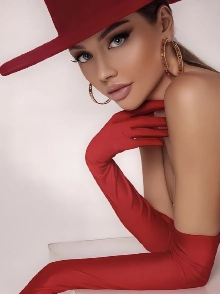 Русский промпт: Photo of a beautiful African-American woman with fair skin and blue eyes, wearing a red hat, gold hoop earrings, and red gloves. She is posing with one hand on her chin and the other resting on a white cube. The background is a plain white wall. The lighting is soft and even, highlighting her features. The woman has a confident and alluring expression. The image has a high quality and professional feel. | Original prompt: Photo of a beautiful African-American woman with fair skin and blue eyes, wearing a red hat, gold hoop earrings, and red gloves. She is posing with one hand on her chin and the other resting on a white cube. The background is a plain white wall. The lighting is soft and even, highlighting her features. The woman has a confident and alluring expression. The image has a high quality and professional feel.