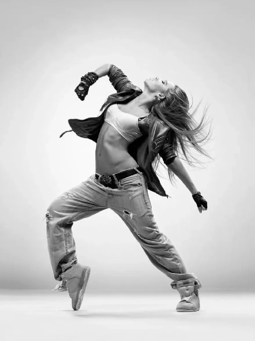 Русский промпт: Черно -белая фотография молодой женщины с длинными, текущими волосами, энергично танцующей. На ней черная кожаная куртка, белый топ и рваные джинсы. Ее руки вытянуты по бокам, и она носит белые кроссовки. Фон простальный, светло -серый. Освещение мягкое и равномерное, подчеркивая ее изгибы и текстуру ее джинсов. Изображение имеет высококачественный, профессиональный вид. | Original prompt: A black and white photograph of a young woman with long, flowing hair, dancing energetically. She is wearing a black leather jacket, a white crop top, and ripped jeans. Her arms are stretched out to the sides, and she is wearing white sneakers. The background is a plain, light grey. The lighting is soft and even, highlighting her curves and the texture of her jeans. The image has a high-quality, professional look.